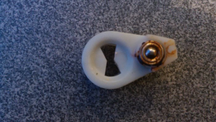 Oval låsbricka i plast med metallskruv på granitbänk, tillbehör till låscylinder.