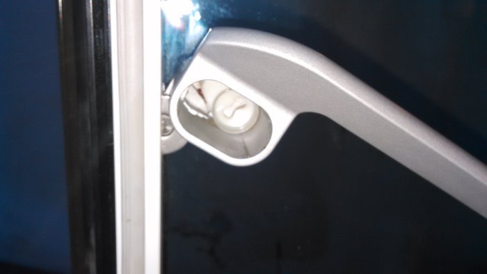 Dörrhandtagets insida med synlig vit plastbit och låsbrickans hållare, redo för låscylinderinstallation.