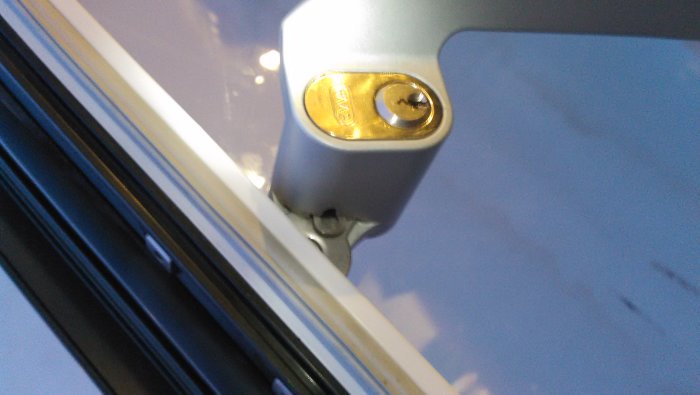 Oval låscylinder i dörrhandtag med synlig låsbricka och cylinderskruv.