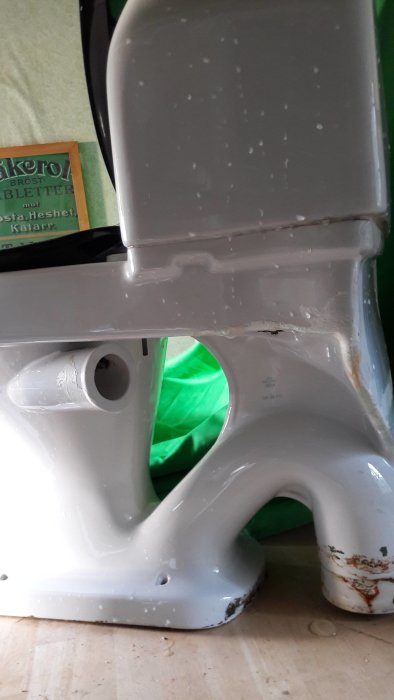 Toalettstol med sidoanslutning för avlopp, synlig korrosion och smuts, närbild.
