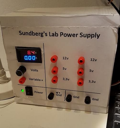 DIY justerbart labbströmförsörjning med digital display, knappar och anslutningar på en träpanel.