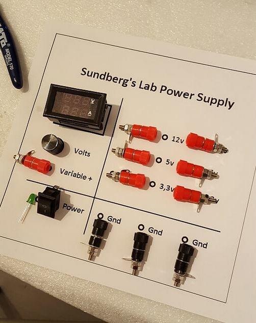 DIY justerbar laboratorieströmförsörjning med voltmätare, spänningsutgångar och på/av-knapp på märkt panel.