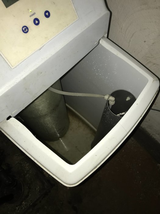 Vattenavhärdare med öppen salttablettbehållare och låg vattennivå, märkt Erie Water Treatment.
