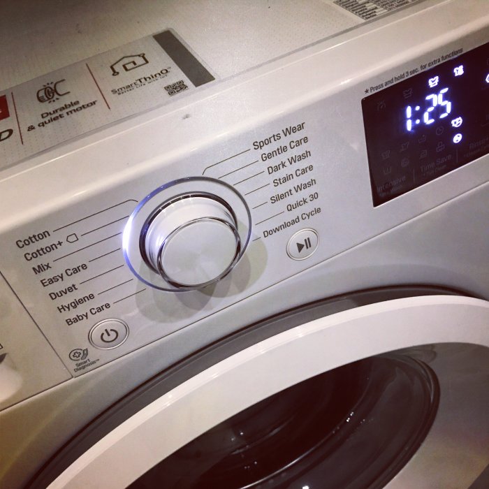Närbild på en modern tvättmaskin med inställningsvred och digital display som visar 1:25.