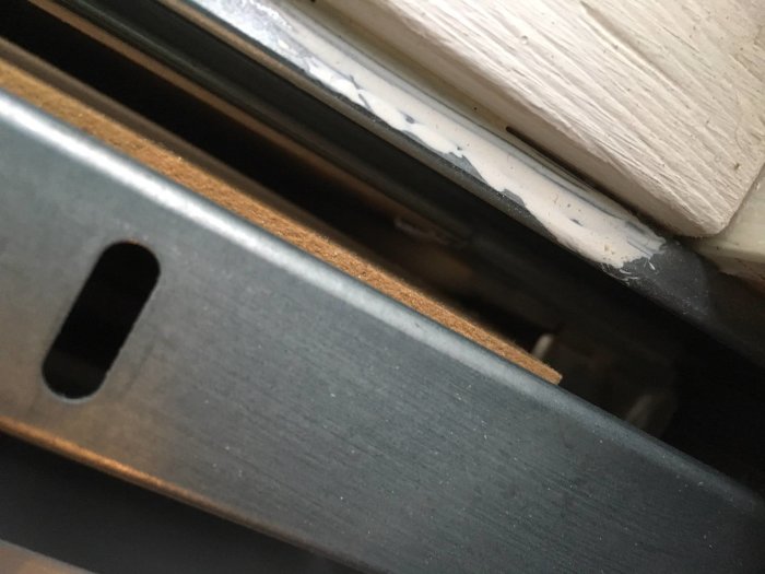 Glipan på 10 mm mellan en dörrkarm och ett metallfäste i en byggkonstruktion.