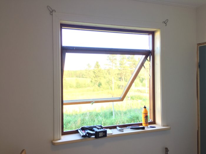 Nyinstallerat fönster med limfogade salningar och fönsterbräda redo för målning, samt verktyg på brädan.