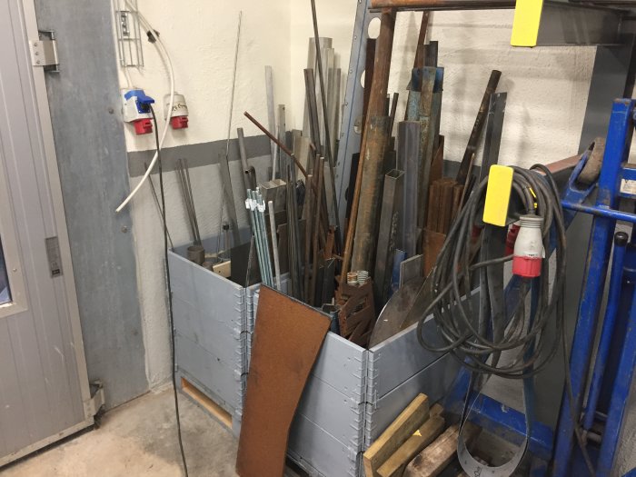 Organiserat material i ett garage med staket runt diverse plåtar och småmaterial.