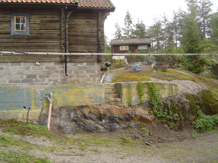 Tomt efter sprängning med avjämnad mark och grundmur mot berg, före byggandet av altan.