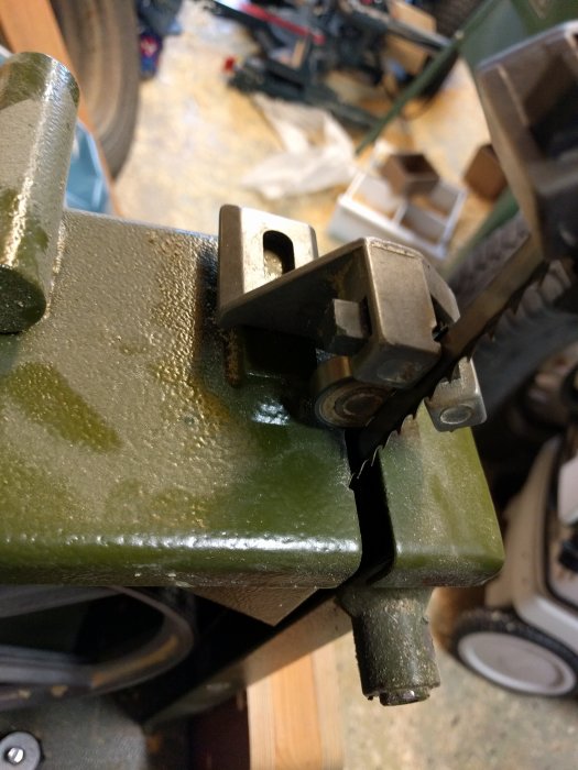 Bild av en bandsåg i ett garage med fokus på bladstyrningen nära sågbordet.