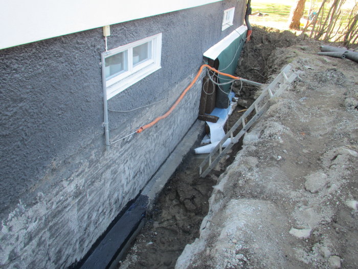 Renovering av husgrund med ny gjuten betongklack och pågående dräneringsarbete.