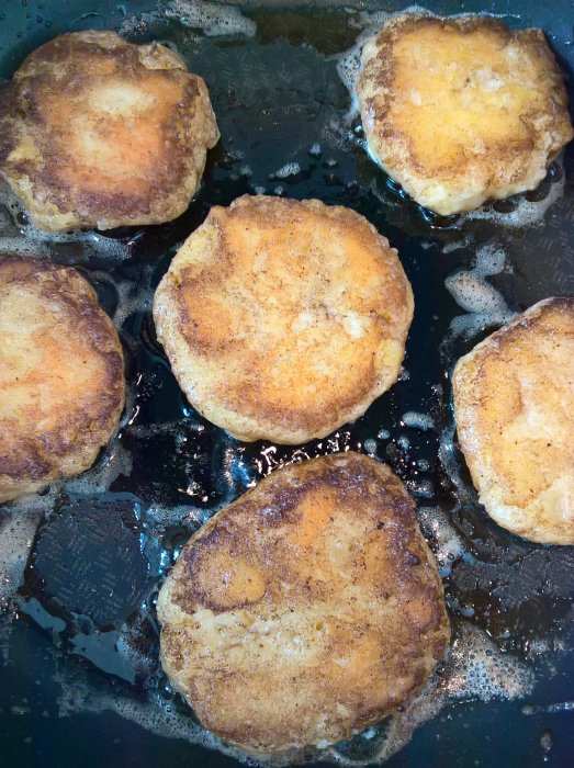 Hemlagade potatisbullar steks i smör i en stekpanna, gyllenbruna och redo att ätas.