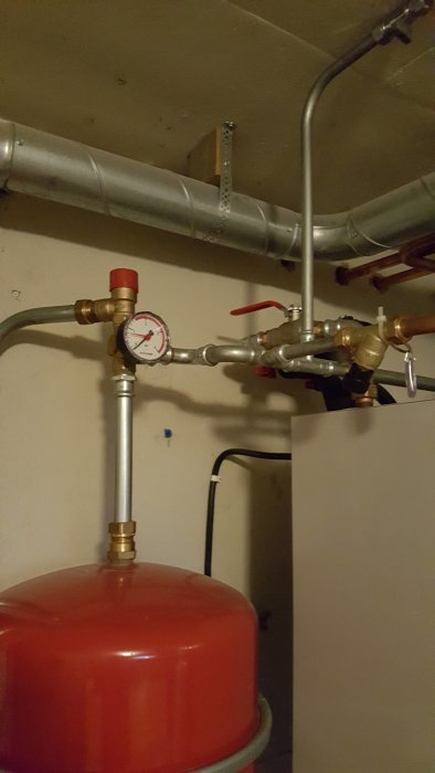 Expansionskärl med tryckmätare och röranslutningar i en villa från 60-talet, risk för vattenläckage.