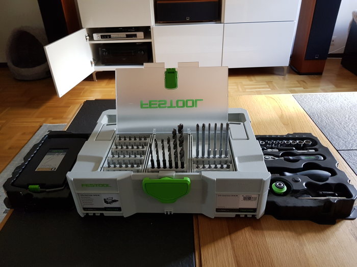 Festool borr- och bitssats i öppen förvaringsväska på ett golv i hemmiljö.