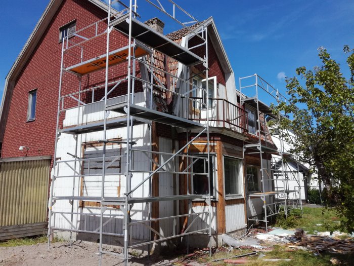 Ett 20-tals hus under renovering med ställningar runtom och delvis borttagen ytterpanel.