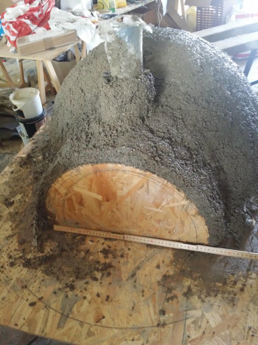 Kupuverhoiltu rakennelma, joka näyttää olevan valmistettu vermikuliittibetoni-seoksesta, sijaitsee puupinnalla, ja siinä on mitta-asteikko edessä.