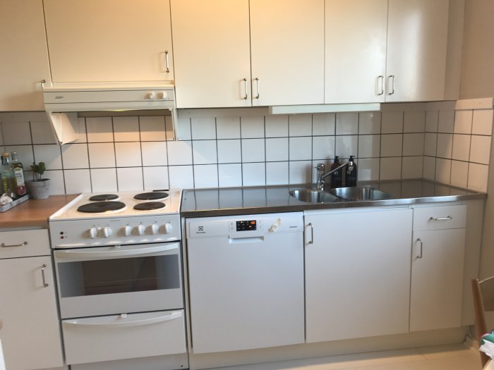 Renoverat kök med nymålade fogar mellan vita kakelplattor ovanför vit köksinredning.