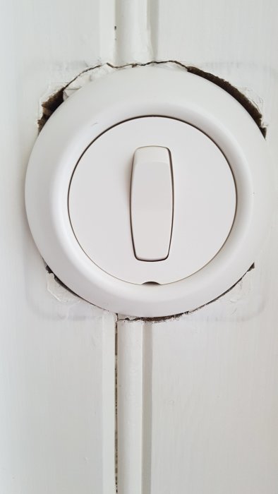 Vit strömbrytare från Renova monterad på pärlspontvägg med ojämnt sågade kanter.