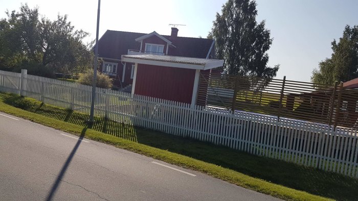 Ett rött hus med nyinstallerade vindskivor och otillräckligt täckande vit plåt på taket.