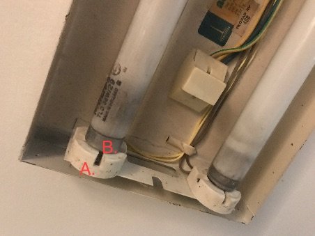 Öppet eluttag med två märkta kablar A och B och en lysrörsarmatur ovanför.