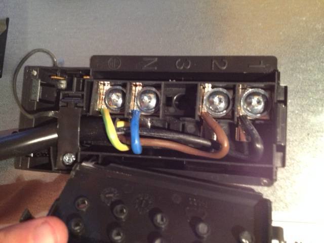 Öppen elkontakt med tre skruvanslutningar och trådar mellan terminal 1 och 2.