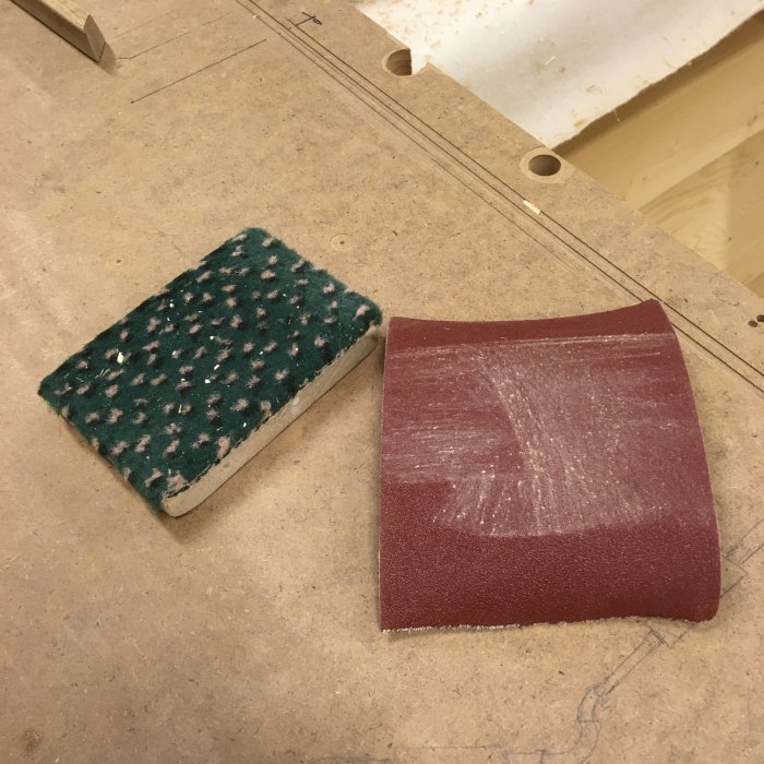 Putskloss med mjuk sida och sandpapper på träskiva, använda för slipning av glaslister.