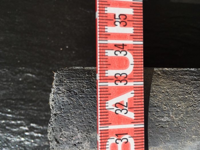 Mätning av takpanna med röd mätsticka som visar mått i centimeter.