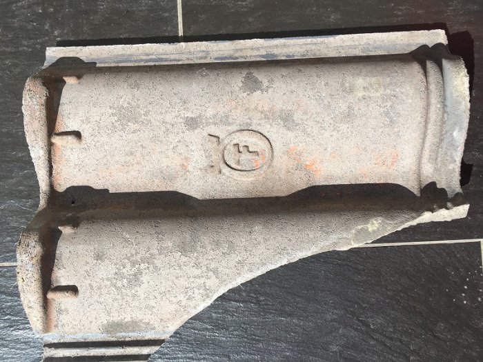 Undersidan av en grå tvåkupig takpanna med loggan för Örebropannan synlig i mitten.