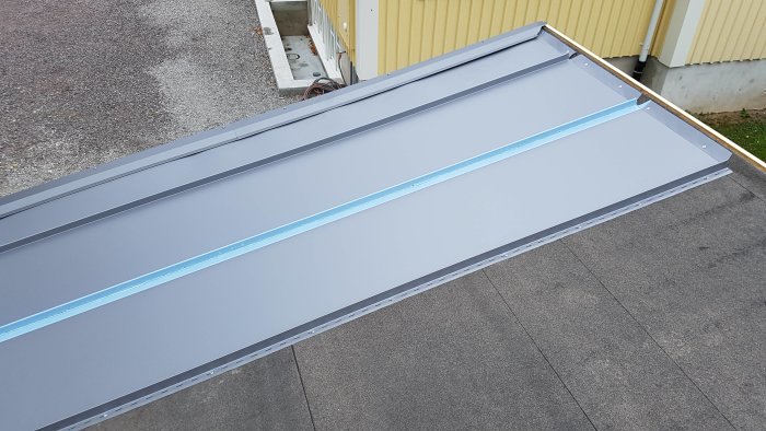 Nytt grått plåttak med synlig takpapp och råspont undertill.