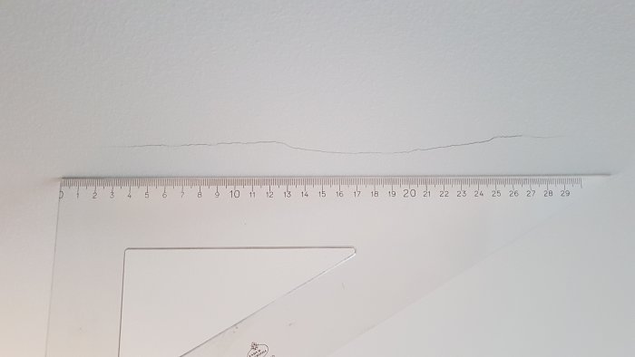 Spricka i taket med en linjal som visar längden på skadan.