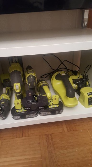 Samling av Ryobi verktyg inklusive borr, batterier och laddare på en hylla.