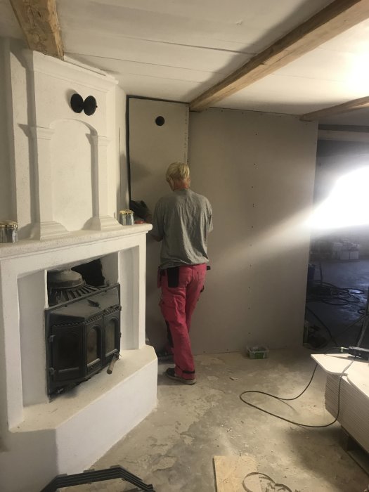 Person som arbetar med att förbereda installation av högtalare och TV-fäste i ett tak under renovering.