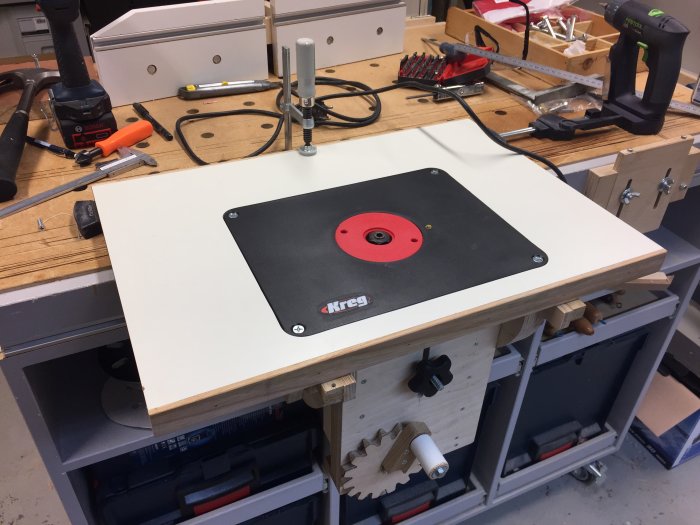 Monterad Kregs fräsplatta insänkt i en arbetsbänks yta med verktyg och frästillbehör omkring.