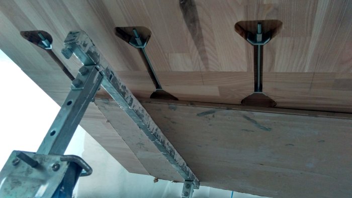 Underifrånvy av bänkskivor med monterade kopplingsbeslag och verktyg för justering.