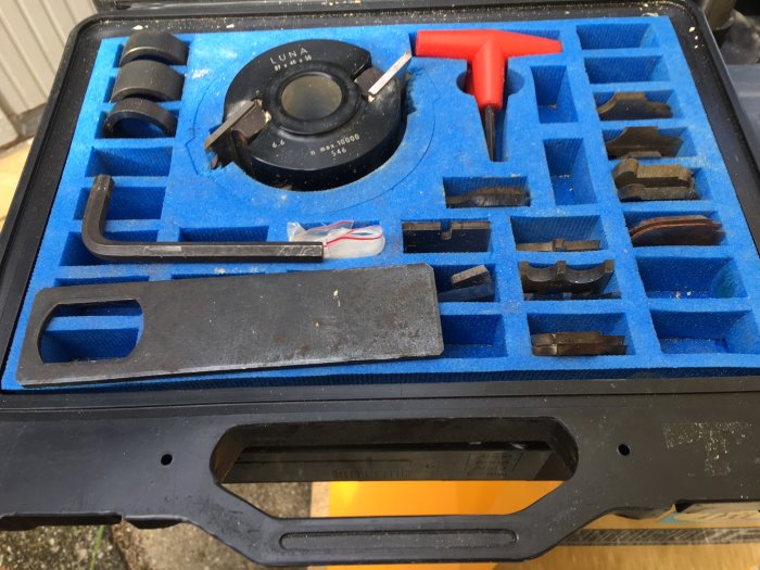 Låda med träbearbetningskutter och tillbehör, vissa i blått skum, med tydliga användningstecken.