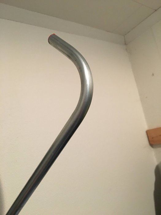 Elförzinkat rör med böj, bättre form än kopparrör, mot vit vägg och tak bakgrund.