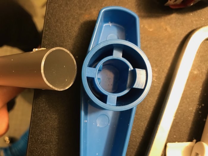 En uppvisning av ett 20mm aluminiumrör nära ett blått poolfiltervred med en 18mm öppning för en förlängning.