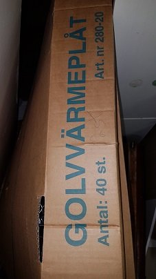 En liggande brun kartong för golvvärmeplåtar med text som indikerar att det är en produkt för golvvärme.