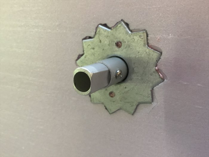 Presspassat vred i hål med taggig metallplatta monterad på en vägg.