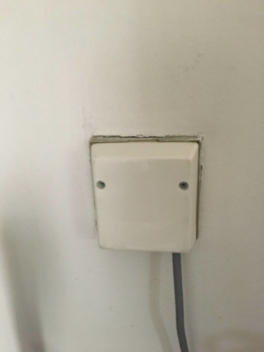 Nyinstallerad vit dimmer på vägg med synlig kabelföring och spacklade kanter runt dosan.