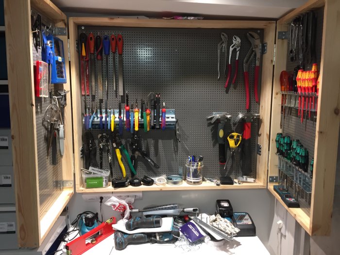 Ett öppet verktygsskåp med ordnat arrangemang av hammare, skruvmejslar och tänger.
