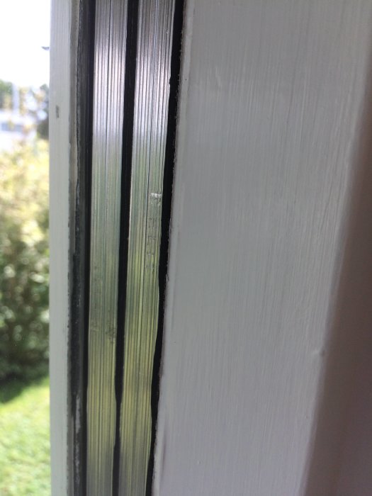 Närbild på vita fönsterspröjs med texten 'Elit' synlig genom glaset.