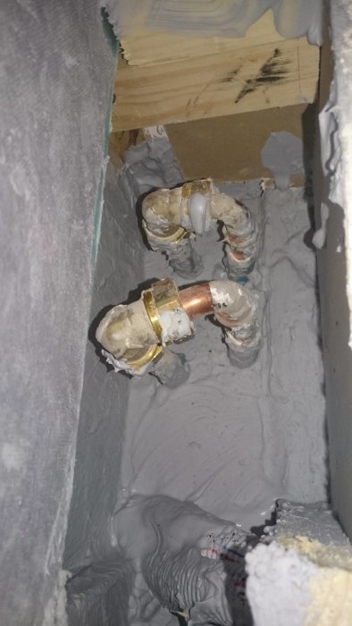 Rörläggarkoppling mellan gammal radiatorslinga och kopparrör i grått isolerskum.