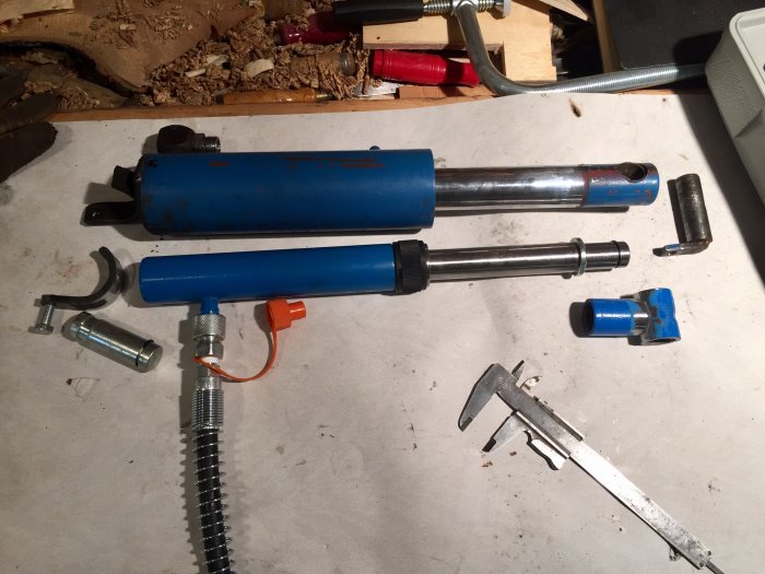 Hydraulcylindrar, komponenter och verktyg på arbetsbänk för att göra nya infästningar.