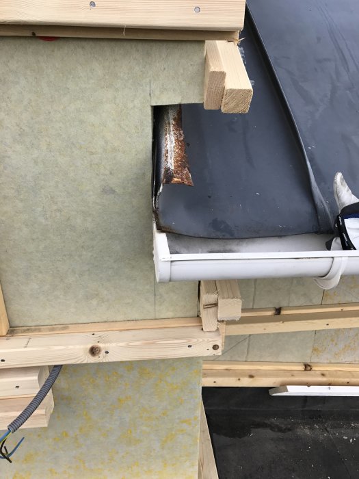 Plåttak som möter en ny fasad och knutbräda, risk för vattenintrång där taket går in under fasaden.