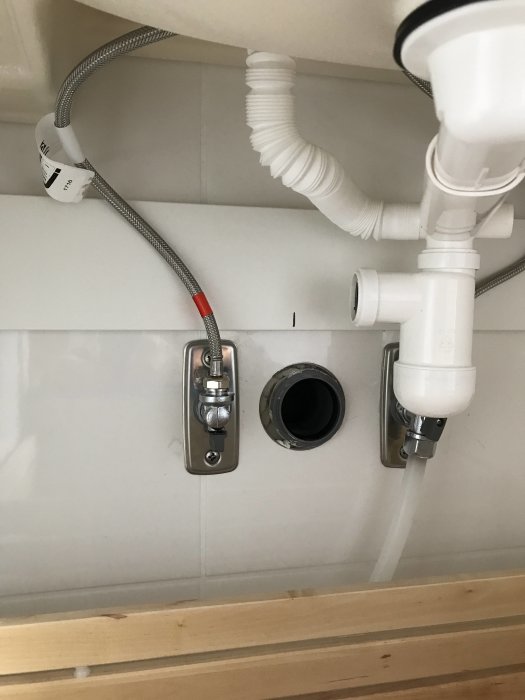 Avloppsrör i vägg med för högt utstick för IKEA Odensvik handfat, punglåset neddraget, problematisk installation.