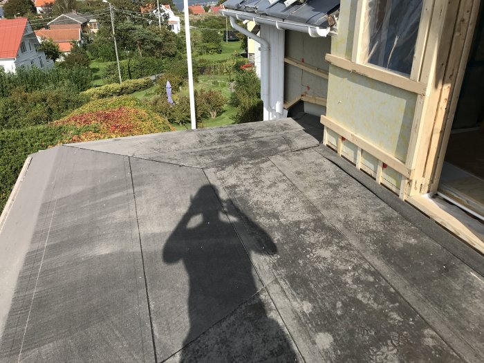 Bild på ett hus under ombyggnation med synlig skugga av en person på ett gammalt tak.