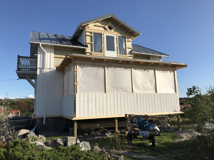 Hus under renovering med synliga vita hängrännor och pågående takarbete.