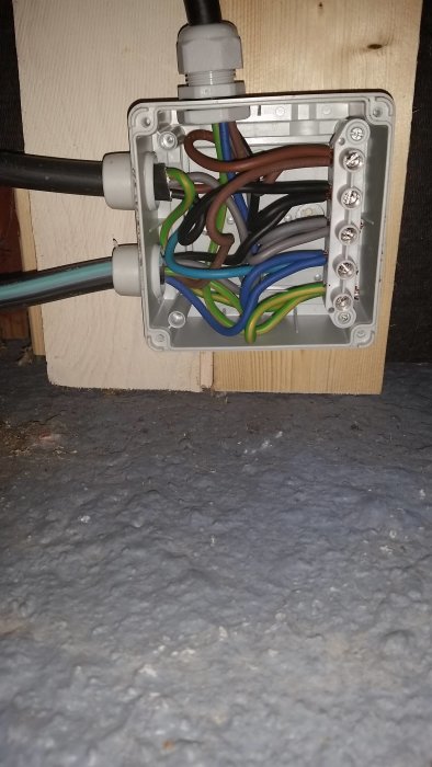 Elektrisk kopplingsdosa med snyggt draget kablage och rörinstallation på ett trägolv.