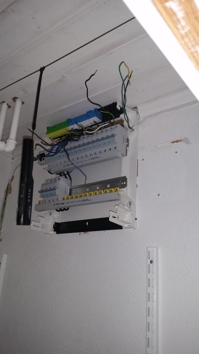 Nyinstallerat elskåp på en vägg med öppna säkringsdosor och utspridda elkablar som väntar på märkning.