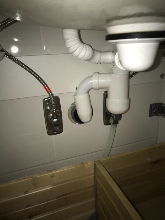 Rörsystem under handfat med nyinstallerad 32 mm böjd pip inpassad bakom låda.